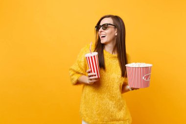 Neşeli genç kadın arayan bir kenara izlerken film film tutun kova patlamış mısır, plastik bardak kola veya izole sarı zemin üzerine soda 3d IMAX bardaklarda. İnsanlar sinema, samimi duygular yaşam tarzı