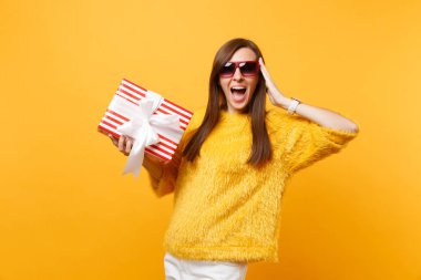 Kırmızı kutu hediye, holding kırmızı gözlük el yüz, yakın koruma heyecanlı kadında zevk tatil parlak sarı arka plan üzerinde izole mevcut. İnsanlar samimi duygular, yaşam tarzı. Reklam alanı