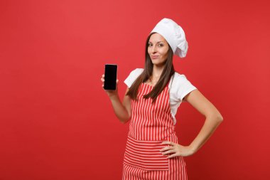 Ev hanımı kadın şef aşçı ya da çizgili önlük t-shirt toque şefler şapkalı kırmızı duvar arka plan üzerinde izole baker. Kadın cellphone yükselme içerik için boş ekran ile tutun. Kopyalama alanı kavramı alay