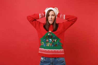 Şaşkın üzgün Santa içindeki genç kız örgü kazak, Noel şapka baş üzerinde izole parlak kırmızı duvar arka plana tutunmuş. Mutlu yeni yıl 2019 kutlama tatil parti kavramı. Kopyalama alanı alay