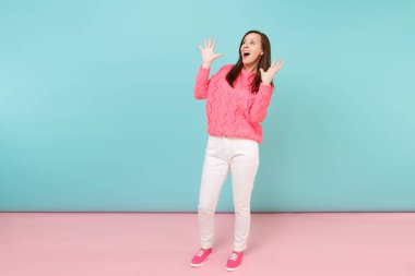 Tam uzunlukta örme gül kazaklı gülümseyen genç kadın portresi, beyaz parlak pembe mavi pastel duvar arka planda Studio izole poz pantolon. Moda yaşam tarzı kavramı. Kopyalama alanı alay