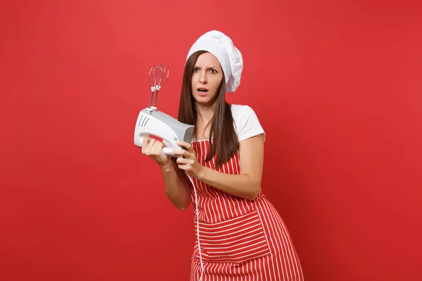 Housewife female chef cook or baker in striped apron white t-shirt toque chefs hat isolated on red wall background. Woman hold kitchen mixer, cook Christmas ginger biscuit. Mock up copy space concept