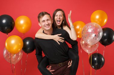 Parlak kırmızı arka plan hava balonu üzerinde kutluyor Doğum günü tatil partisi izole siyah giysili genç çift çarpıcı. St. Valentine's Dünya Kadınlar Günü mutlu yeni yıl 2019 kavramı.