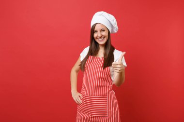 Ev hanımı kadın şef aşçı ya da baker izole kırmızı duvar arka plan üzerinde çizgili önlük, beyaz tişört, toque şefler şapkalı. Güzel gülümseyen kahya kadın başparmak göstermek yukarıya. Kopyalama alanı kavramı alay