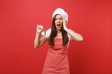 Ev hanımı kadın şef aşçı ya da baker izole kırmızı duvar arka plan üzerinde çizgili önlük, beyaz tişört, toque şefler şapkalı. Korkmuş kadın tutun el retro çalar saat içinde acele et. Kopyalama alanı kavramı alay