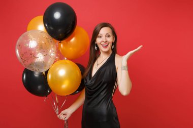 Güzel genç kız küçük siyah elbiseli bir kenara hava balonları izole kırmızı zemin üzerine tutarak işaret eden bir ele kutluyor. St. Valentine's gün, mutlu yeni yıl, Doğum günü mockup tatil parti konsept