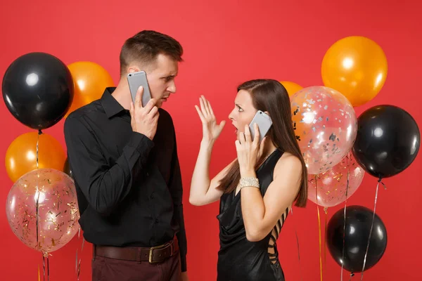 Couple stand back to back talking on cellphone celebrating birthday holiday party isolated on red background air balloons. St. Valentine International Women Day Happy New Year 2019 concept. Mock up