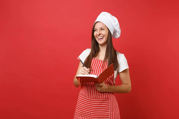 主婦女性シェフやストライプ エプロン白 シャツ トーク シェフ帽子赤い壁の背景に分離のパン屋 笑みを浮かべて女性保留メモ帳レシピ本とペンを料理します コピー スペース コンセプトをモックアップします — ストック写真