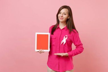 Pastel duvar arka planda, stüdyo portre izole pembe ipek kurdele tutun tablet pc ile gül giysili bir kadın. Tıbbi sağlık Jinekolojik Onkoloji, meme kanseri bilinçlendirme kavramı sahte alanı