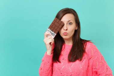 Örgü pembe kazaklı elinde tutan, mavi turkuaz duvar arka planda, stüdyo portre izole çikolata ile göz kapsayan karışık genç kadın. İnsanlar yaşam tarzı kavramı. Kopyalama alanı alay