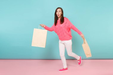 Tam uzunlukta örme gül kazaklı gülümseyen genç kadın portresi, beyaz parlak pembe mavi pastel duvar arka planda Studio izole poz pantolon. Moda yaşam tarzı kavramı. Kopyalama alanı alay