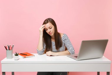 Sinir bozucu kadın yandan eğilerek çaresizlik içinde oturup, arıyorsunuz işe beyaz masa başında pastel pembe arka plan üzerinde izole çağdaş pc dizüstü bilgisayar ile. Başarı iş kariyer kavramı. Kopya alanı