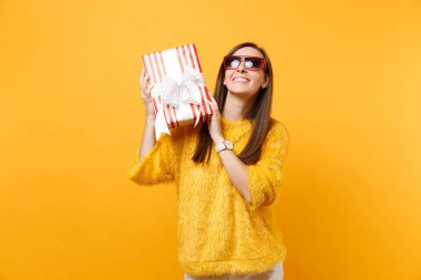 Kırmızı kutu hediye, mevcut durumun arıyorum kırmızı gözlük gülümseyen kadın kutluyor, parlak sarı arka plan üzerinde izole tatil keyfini. İnsanlar samimi duygular, yaşam tarzı. Reklam alanı