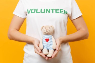Beyaz kadın portresi t-shirt ile yazılı yazıt yeşil başlık gönüllü oyuncak ayı peluş oyuncak sarı arka plan üzerinde izole tutun. Gönüllü ücretsiz destek yardım, sadaka grace iş kavramı