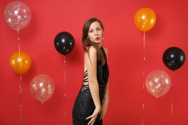 Küçük siyah elbise üfleme dudakları parlak kırmızı arka plan hava balonları kutluyor tutkulu genç kadın. Sevgililer Dünya Kadınlar Günü mutlu yeni yıl Doğum günü mockup tatil parti konsept