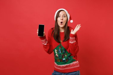 Hayret Noel Baba kız Yayilim eller, kırmızı zemin üzerine izole boş boş ekran ile cep telefonu tutan şaşırttı. Mutlu yeni yıl 2019 kutlama tatil parti kavramı. Kopyalama alanı alay