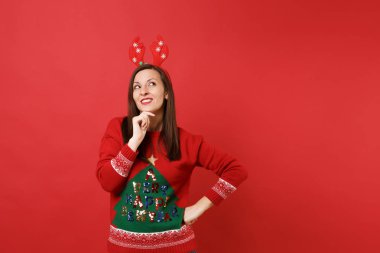 Dalgın Noel Baba kız baş koymak eller yukarıda görünümlü dekoratif geyik boynuzları üzerinde kırmızı zemin üzerine izole çene pervane eğlenceli. Mutlu yeni yıl 2019 kutlama tatil parti kavramı. Kopyalama alanı alay