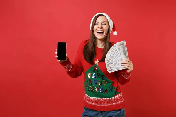 赤の背景に分離された空白の空の画面でドル紙幣現金と携帯電話をたくさん束をもつサンタ少女を笑っています 幸せな新しい年 2019年お祝い休日党概念 — ストック写真