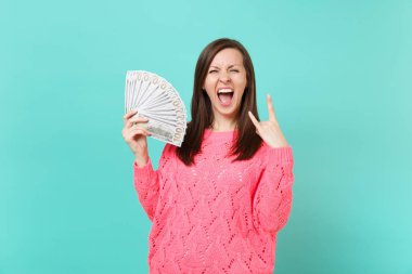 Heavy metal rock boynuzları tasvir eden deli kadın çığlık, pembe kazaklı tutun çok dolar banknotlar nakit para, demet izole üzerinde mavi arka plan oturum açın. İnsanlar yaşam tarzı kavramı. Kopyalama alanı alay