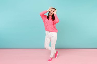 Tam uzunlukta örme gül kazaklı gülümseyen genç kadın portresi, beyaz parlak pembe mavi pastel duvar arka planda Studio izole poz pantolon. Moda yaşam tarzı kavramı. Kopyalama alanı alay
