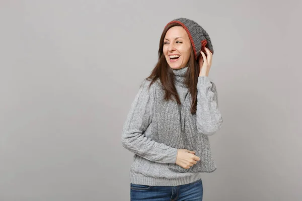 灰色のセーター 帽子スカーフ よそ見で笑う女性は 頭に孤立した灰色の背景に手を置きます 健全なライフ スタイル の心から感情 寒い季節の概念 コピー スペースをモックアップします — ストック写真