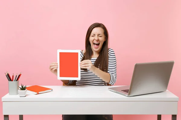 空白の空の画面を目を閉じて保持するタブレット コンピューターと大喜びの女性ピンク色の背景に分離された現代的な ラップトップ ホワイト デスクで仕事を座る ビジネス キャリアを達成 コピー スペース — ストック写真