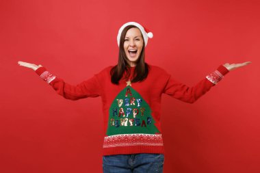 Ellerini kenara izole kırmızı zemin üzerine işaret neşeli Noel Baba içindeki genç kız örme kazak, eller, yayılan Noel şapka. Mutlu yeni yıl 2019 kutlama tatil parti kavramı. Kopyalama alanı alay