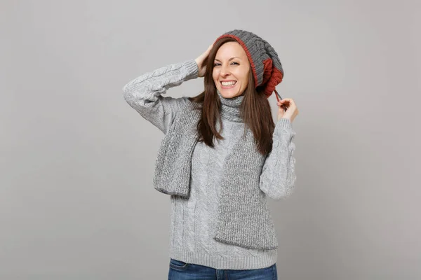 漂亮的年轻女子在灰色毛衣帽子和围巾把手放在头上隔离在灰色背景在工作室 健康时尚生活方式的人真诚的情绪寒冷的季节概念 模拟复制空间 — 图库照片