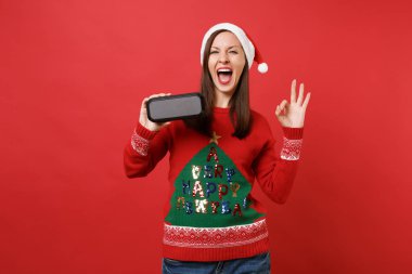 Koruma ağzı açık, gösteren Ok jest, holding taşınabilir kablosuz bluetooth müzik hoparlör izole kırmızı zemin üzerine neşeli Noel Baba kız. Mutlu yeni yıl 2019 kutlama tatil parti konsept