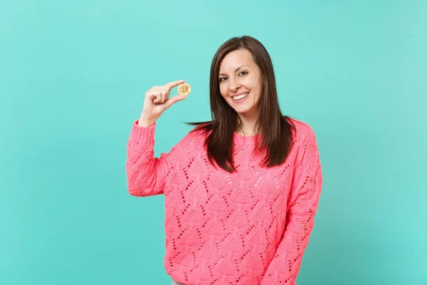 在针织粉红色毛衣中的微笑的年轻女子的肖像举行在手比特币 未来的货币隔离在蓝色绿松石墙的背景下在工作室 人的生活方式概念 模拟复制空间 — 图库照片