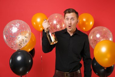 Şişe şampanya parlak kırmızı arka plan hava balonları tutarak siyah klasik gömlek şok genç adam. Sevgililer, Dünya Kadınlar Günü mutlu yeni yıl Doğum günü mockup tatil parti konsept