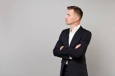 Klasik siyah elbiseli Genç iş adamı portresi, gömlek bir yana, katlanmış elele seyir Studio gri arka plan üzerinde izole. Başarı kariyer servet iş kavramı. Kopyalama alanı alay