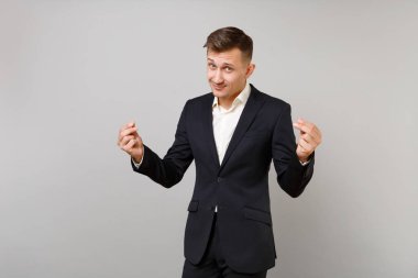 Kendine güvenen genç iş adamı klasik siyah takım elbise sürtünme parmaklar, nakit hareketi, gri arka plan üzerinde izole para talebinde gösterilen. Başarı kariyer servet iş kavramı. Kopyalama alanı alay