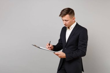 Genç iş adamı klasik siyah takım elbise, gömlek not kağıtları belgeyle Studio gri arka plan üzerinde izole panoya yazmak. Başarı kariyer servet iş kavramı. Kopyalama alanı alay