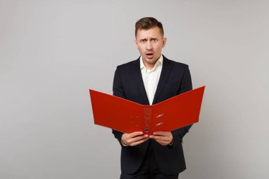 Klasik siyah takım elbise ve gömlek holding kırmızı klasördeki belgeleri belge üzerinde gri arka plan izole için şok endişe genç iş adamı. Başarı kariyer servet iş kavramı. Kopyalama alanı alay
