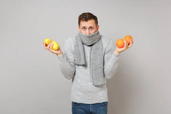Zakłopotany Młody Człowiek Szary Sweter Obejmujące Usta Szalik Trzyma Pomarańcze — Zdjęcie stockowe