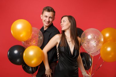 Parlak kırmızı arka plan hava balonu üzerinde kutluyor Doğum günü tatil partisi izole siyah giysili genç çift çarpıcı. St. Valentine's Dünya Kadınlar Günü mutlu yeni yıl 2019 kavramı.