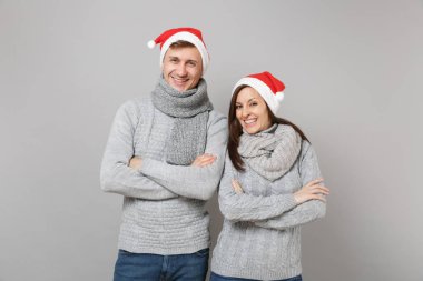 Neşeli eğlenceli çift kız adam Santa Noel şapka gri kazak eşarp gri duvar arka planda, stüdyo portre izole kırmızı. Mutlu yeni yıl 2019 kutlama tatil parti kavramı. Kopyalama alanı alay