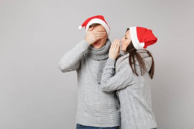 Neşeli eğlenceli çift kız adam Santa Noel şapka gri kazak eşarp gri duvar arka planda, stüdyo portre izole kırmızı. Mutlu yeni yıl 2019 kutlama tatil parti kavramı. Kopyalama alanı alay