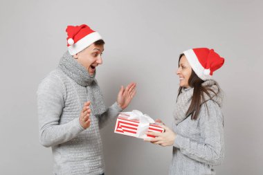 Neşeli eğlenceli çift kız adam Santa Noel şapka gri kazak eşarp gri duvar arka planda, stüdyo portre izole kırmızı. Mutlu yeni yıl 2019 kutlama tatil parti kavramı. Kopyalama alanı alay