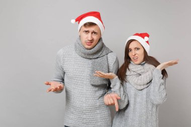 Neşeli eğlenceli çift kız adam Santa Noel şapka gri kazak eşarp gri duvar arka planda, stüdyo portre izole kırmızı. Mutlu yeni yıl 2019 kutlama tatil parti kavramı. Kopyalama alanı alay