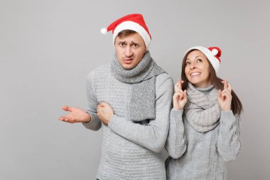 Neşeli eğlenceli çift kız adam Santa Noel şapka gri kazak eşarp gri duvar arka planda, stüdyo portre izole kırmızı. Mutlu yeni yıl 2019 kutlama tatil parti kavramı. Kopyalama alanı alay