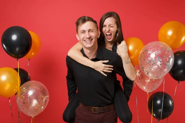 令人惊叹的年轻夫妇在黑色的衣服庆祝生日假期党孤立在明亮的红色背景空气气球 情人节国际妇女节新年快乐2019理念 — 图库照片