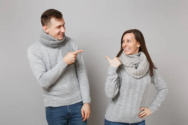 Young cute couple girl guy in gray sweaters, scarves together isolated on grey wall background, studio portrait. Healthy lifestyle, ill sick disease treatment, cold season concept. Mock up copy space