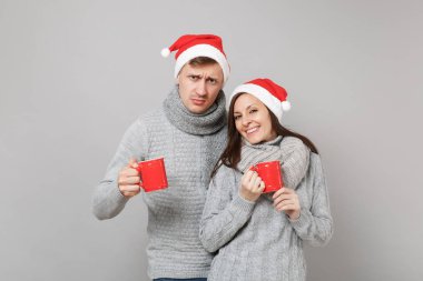 Kırmızı Santa Noel şapka gri kazak eşarp eğlenceli çift kız adam gri duvar arka planda, stüdyo portre izole çay bardak tutun. Mutlu yeni yıl 2019 tatil parti kavramı. Kopyalama alanı alay