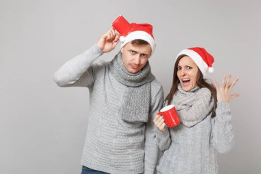 Kırmızı Santa Noel şapka gri kazak eşarp eğlenceli çift kız adam gri duvar arka planda, stüdyo portre izole çay bardak tutun. Mutlu yeni yıl 2019 tatil parti kavramı. Kopyalama alanı alay