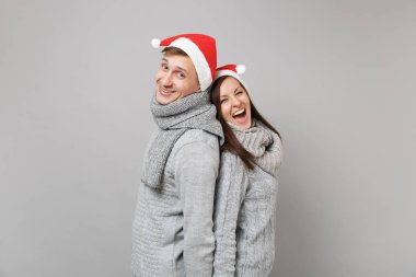 Neşeli eğlenceli çift kız adam Santa Noel şapka gri kazak eşarp gri duvar arka planda, stüdyo portre izole kırmızı. Mutlu yeni yıl 2019 kutlama tatil parti kavramı. Kopyalama alanı alay