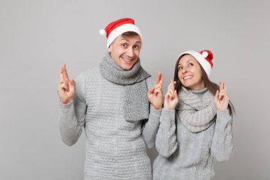 Neşeli eğlenceli çift kız adam Santa Noel şapka gri kazak eşarp gri duvar arka planda, stüdyo portre izole kırmızı. Mutlu yeni yıl 2019 kutlama tatil parti kavramı. Kopyalama alanı alay