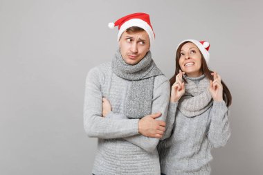 Neşeli eğlenceli çift kız adam Santa Noel şapka gri kazak eşarp gri duvar arka planda, stüdyo portre izole kırmızı. Mutlu yeni yıl 2019 kutlama tatil parti kavramı. Kopyalama alanı alay
