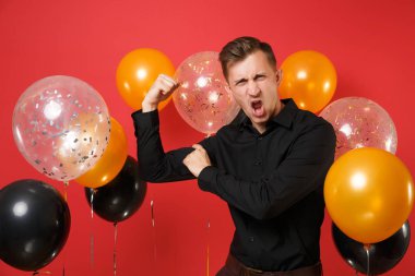 Gösterilen ve pazı parlak kırmızı arka plan hava balonu üzerinde üzerinde işaret parmağı işaret siyah klasik gömlek güçlü genç adam. St. Valentine's Day, mutlu yeni yıl Doğum günü mockup tatil parti konsept